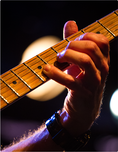 A hand strumming along the neck of a guitar
