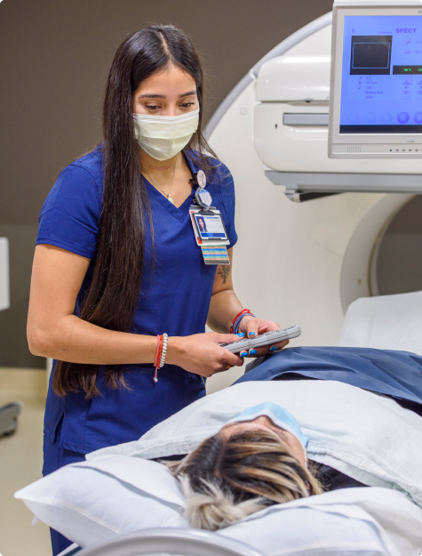 A female imaging professional guiding a patient into a CT scanner 