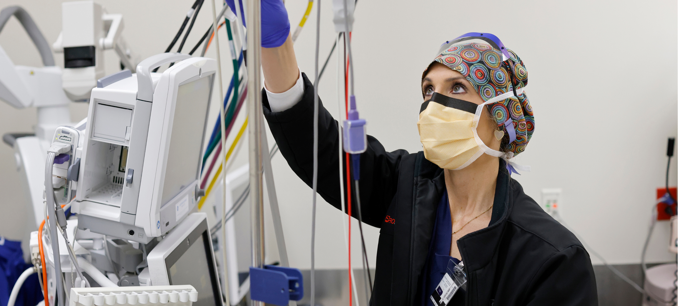 APP_Hero_3 One female certified registered nurse anesthetist (CRNA) looking up and adjusting equipment