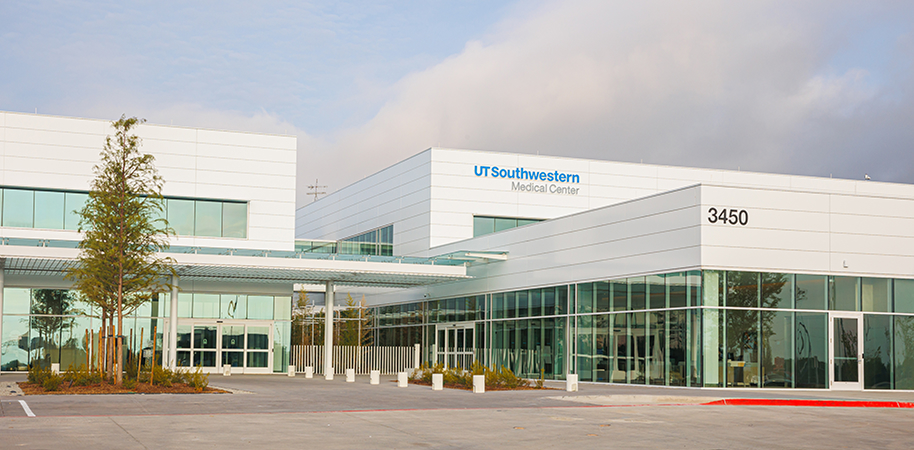 UT Southwestern Medical Center RedBird, a sleek white building with large glass windows and a modern entrance under a cloudy sky.